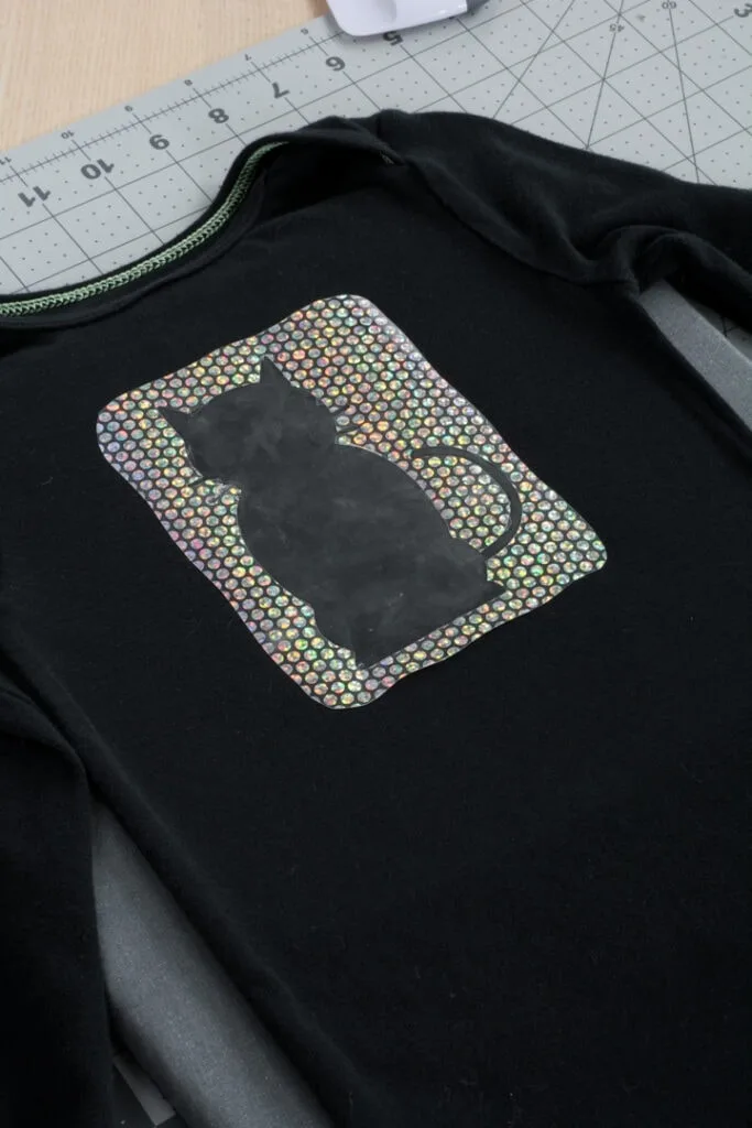 Cricut Holographic Mosaic Iron On cut in a cat shape on a black baby bodysuit