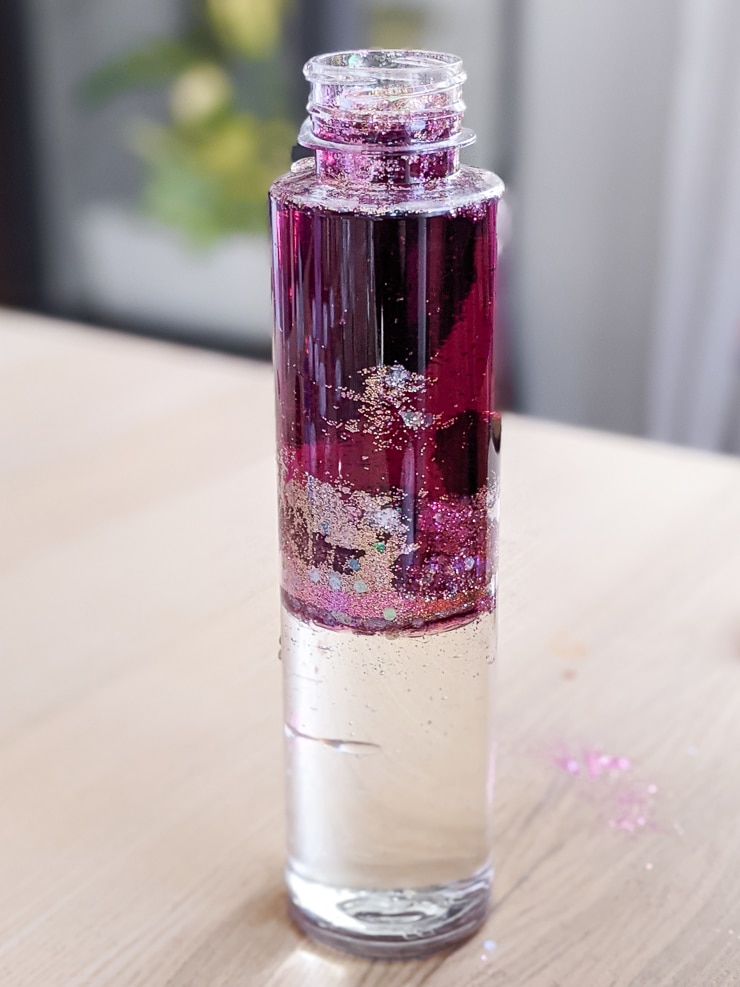 adding glitter and food coloring to the DIY glitter sensory bottle