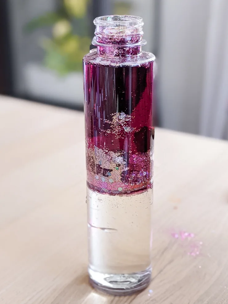 adding glitter and food coloring to the DIY glitter sensory bottle