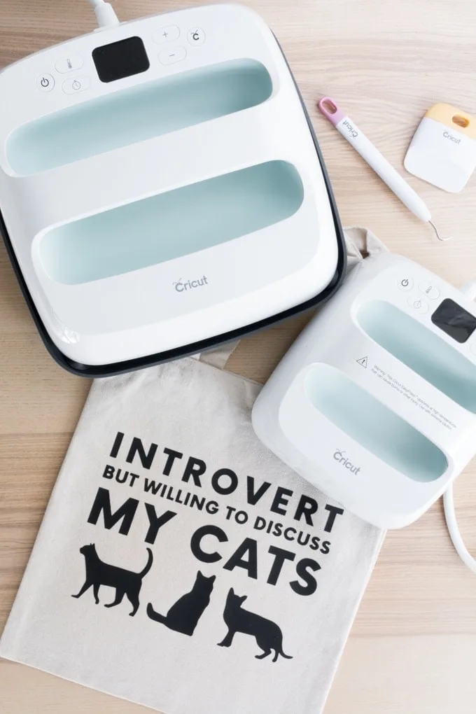 tote bag with a design on it saying introvert but willing to discuss my cats and two Cricut Easypresses
