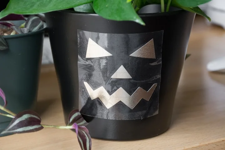jack-o-lantern faces cut out on vinyl and transferred onto a planter pot