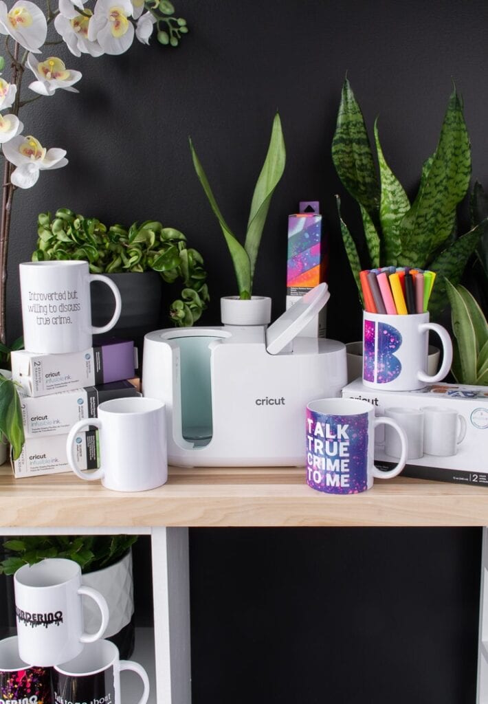 Cricut mug press mug that says talk true crime to me with plants on a table