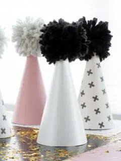 finished scrapbook paper and yarn pom pom party hats