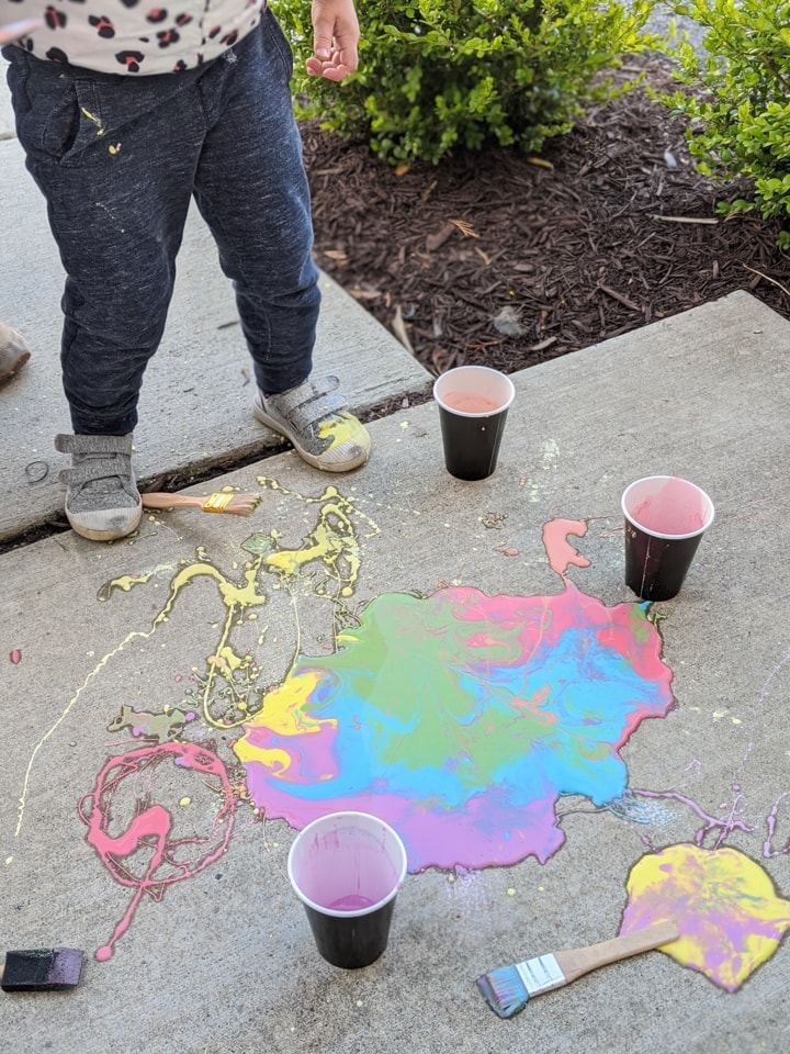 painting on a sidewalk using DIY sidewalk chalk paint