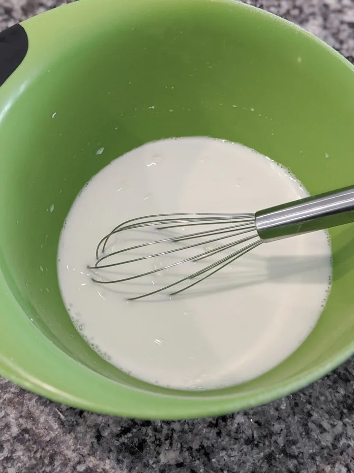 mixing corn starch and water in a bowl with a whisk