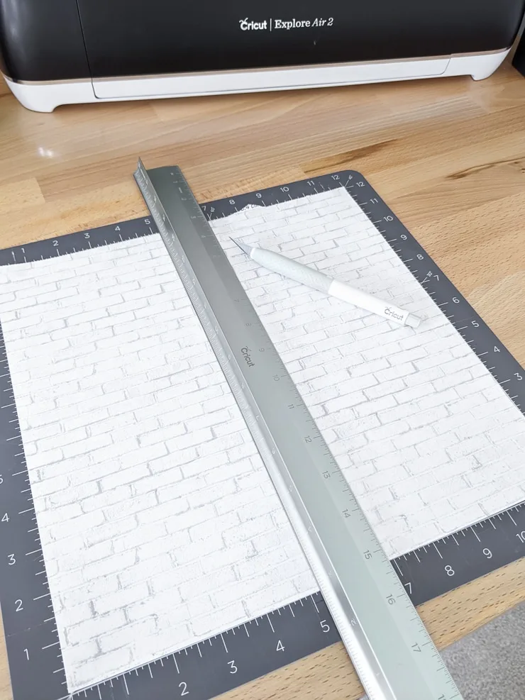 using a ruler and knife to cut scrapbook paper for a dollhouse 