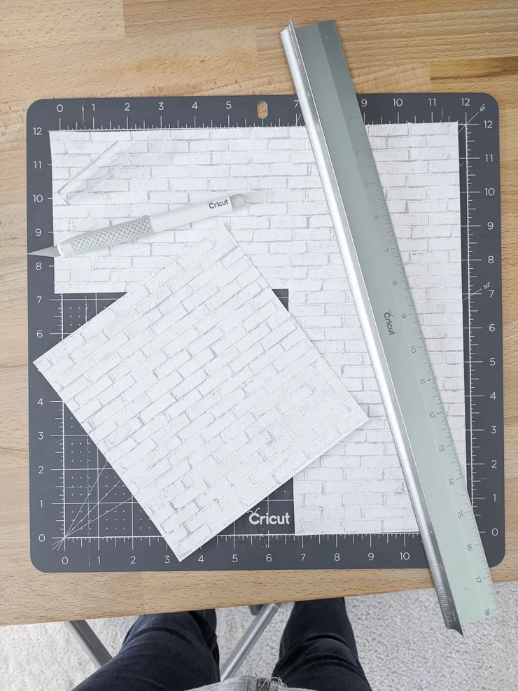 using a ruler and knife to cut scrapbook paper for a dollhouse 