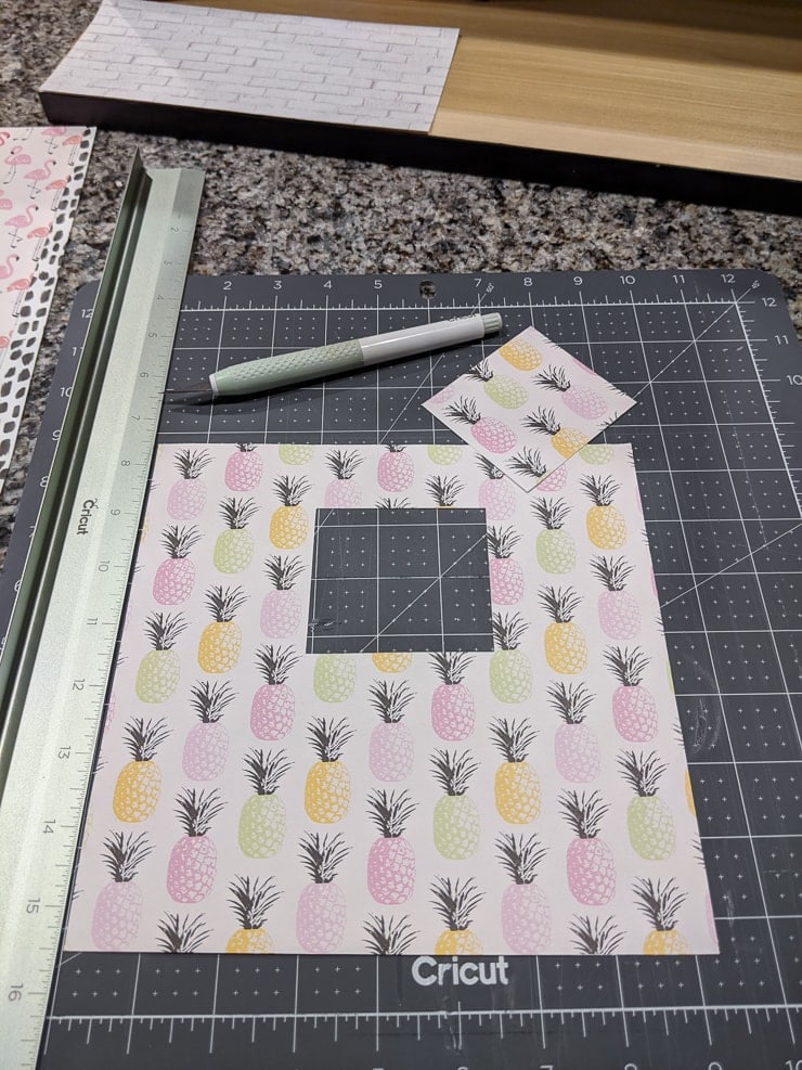 cutting the window out of scrapbook paper for the dollhouse wallpaper
