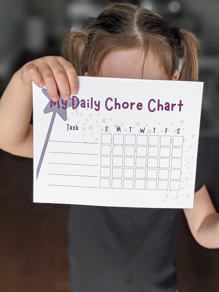 little girl holding a magic-wand-themed daily chore chart
