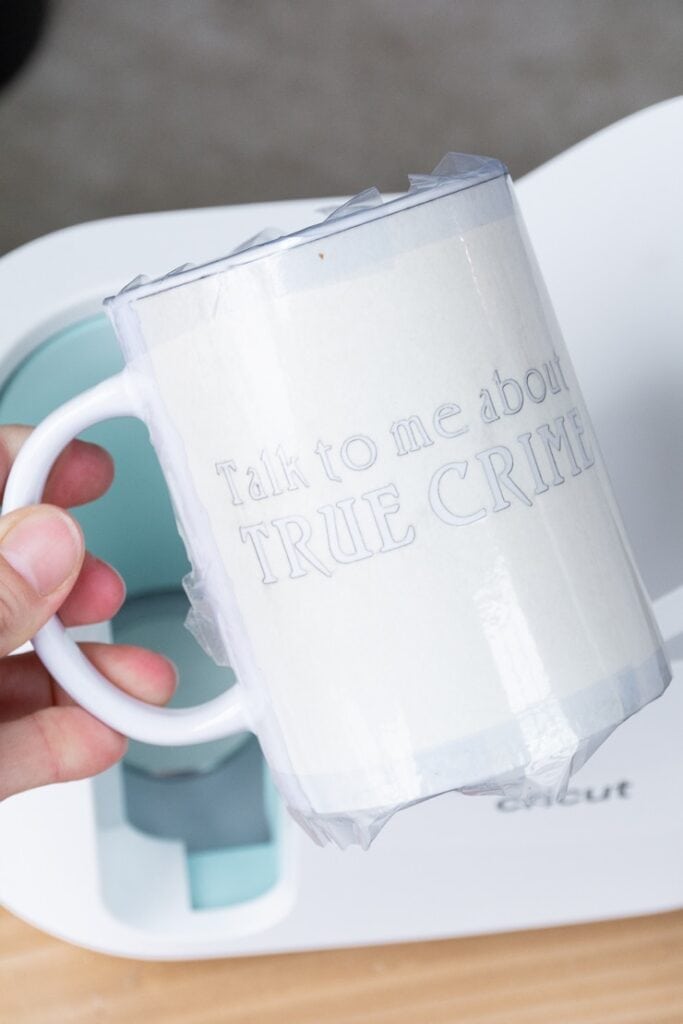 Cricut Infusible Ink transfer sheet on a mug that says "talk true crime to me"
