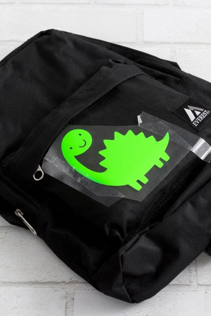 transferring a dinosaur cut out of vinyl to the backpack