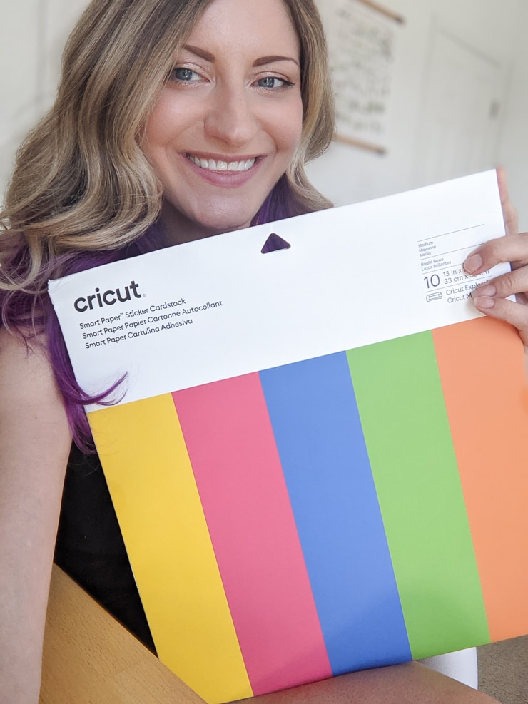 woman holding a package of cricut smart paper sticker cardstock