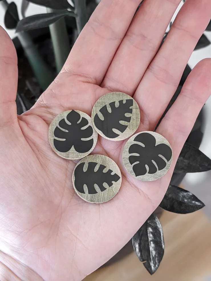 small round pieces of wood with black vinyl leaves on them