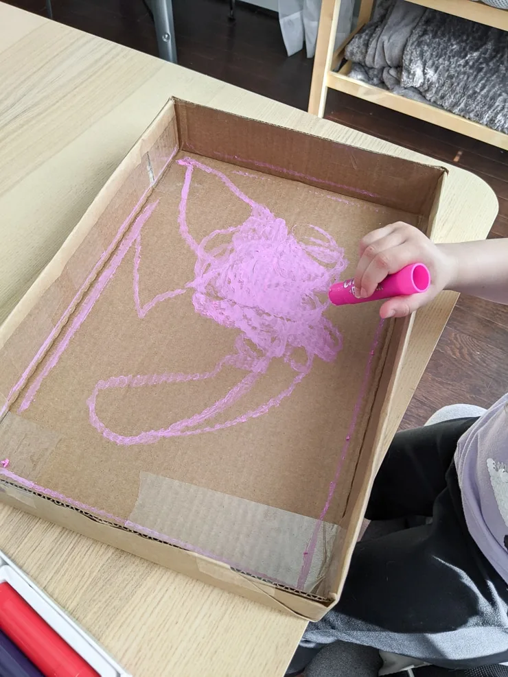 toddler painting a cardboard box