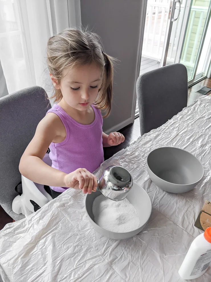 toddler mixing ingredients for DIY slime