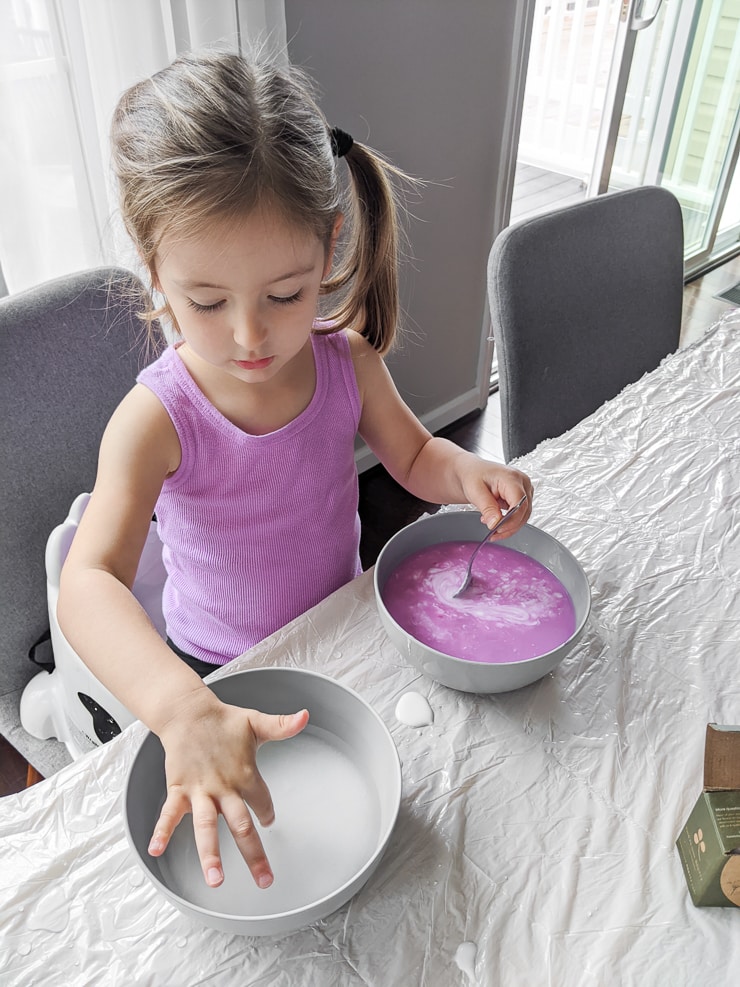 toddler mixing ingredients for DIY slime