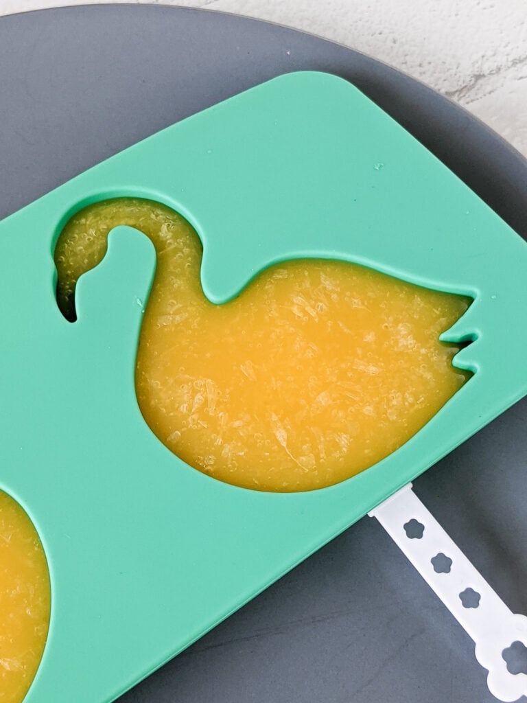 homemade orange juice popsicle made in a flamingo mold