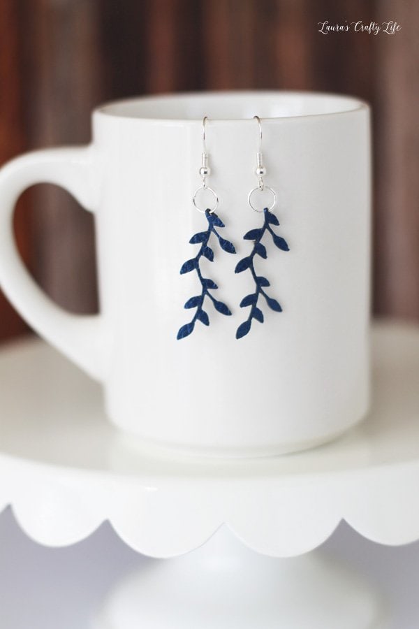 blue branch with leaves earrings hanging on white mug