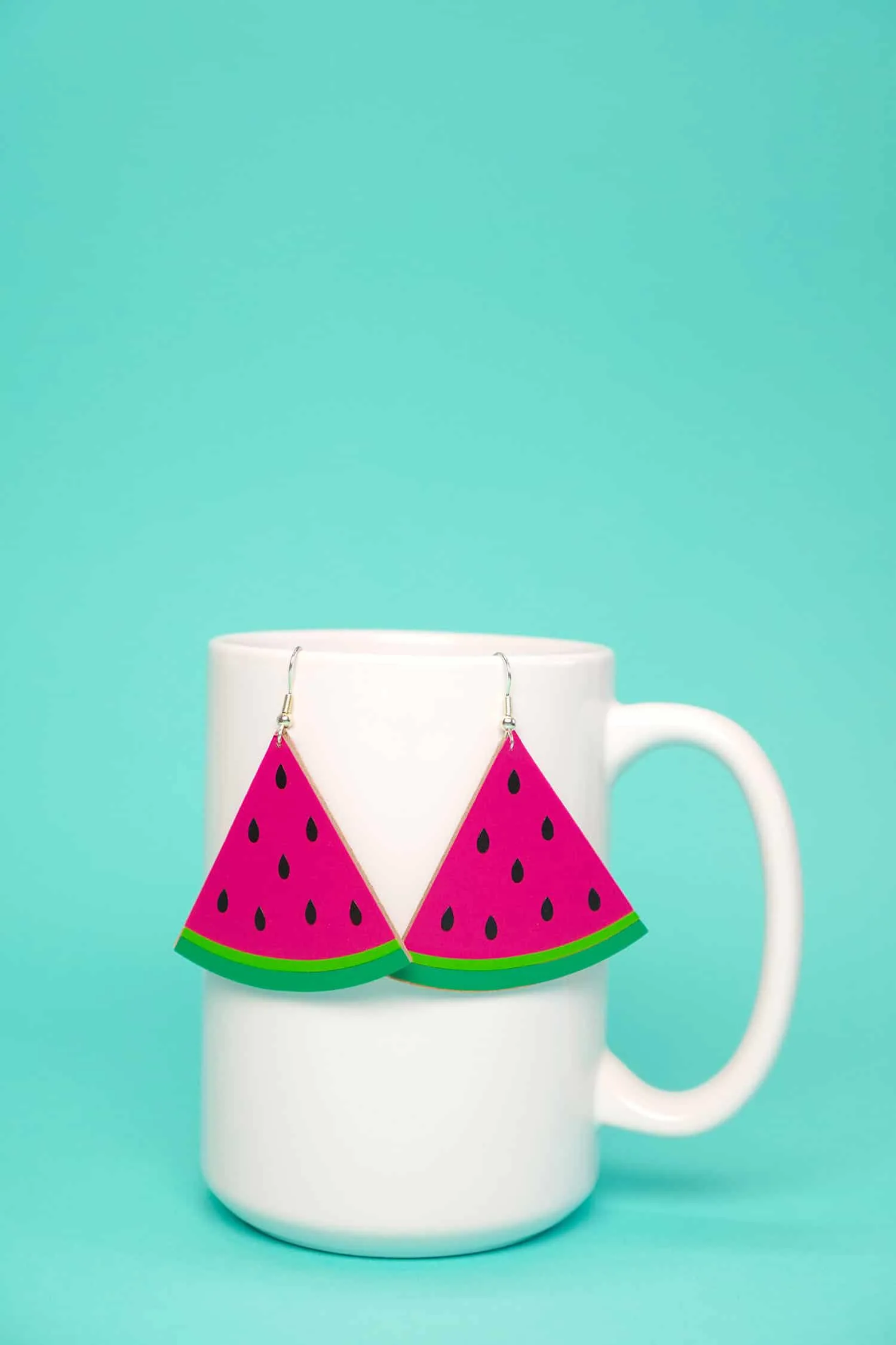 watermelon shaped earrings hanging on a white mug