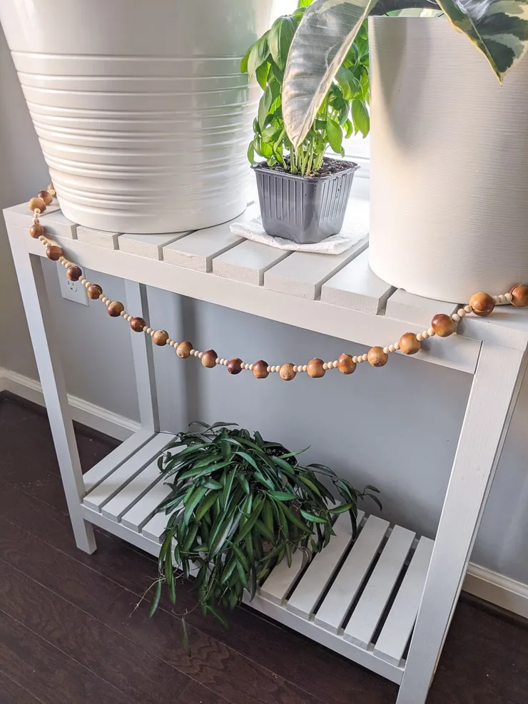 DIY fall garland with wood beads and acorns on a stand with plants