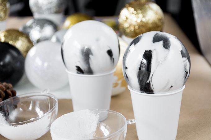 pouring paint inside of clear ornaments