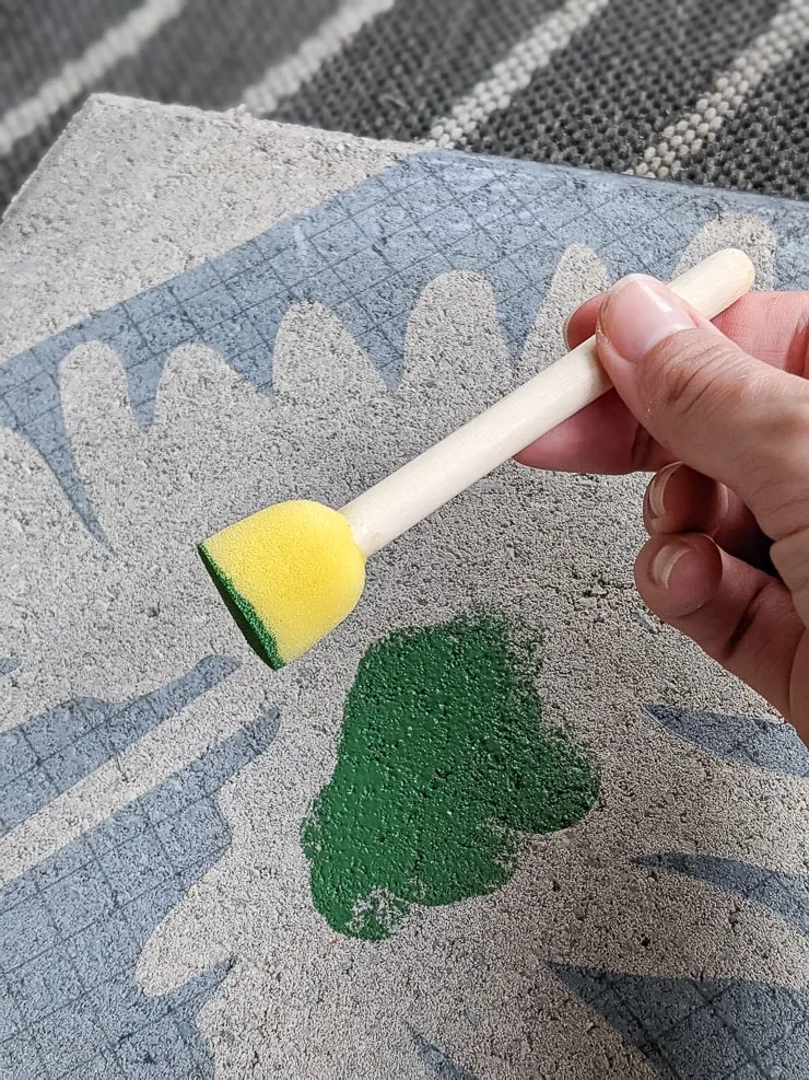 painting the plant leaf vinyl stencil using acrylic green paint and a sponge stencil brush