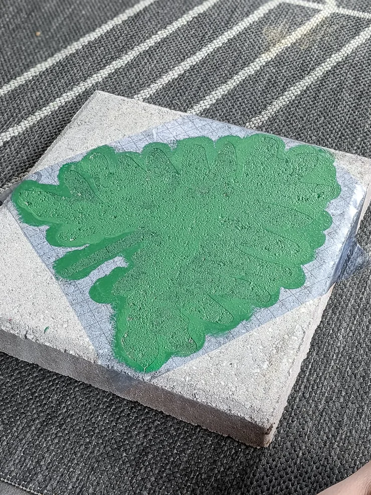 green painted leaf on a concrete paver using a Cricut stencil