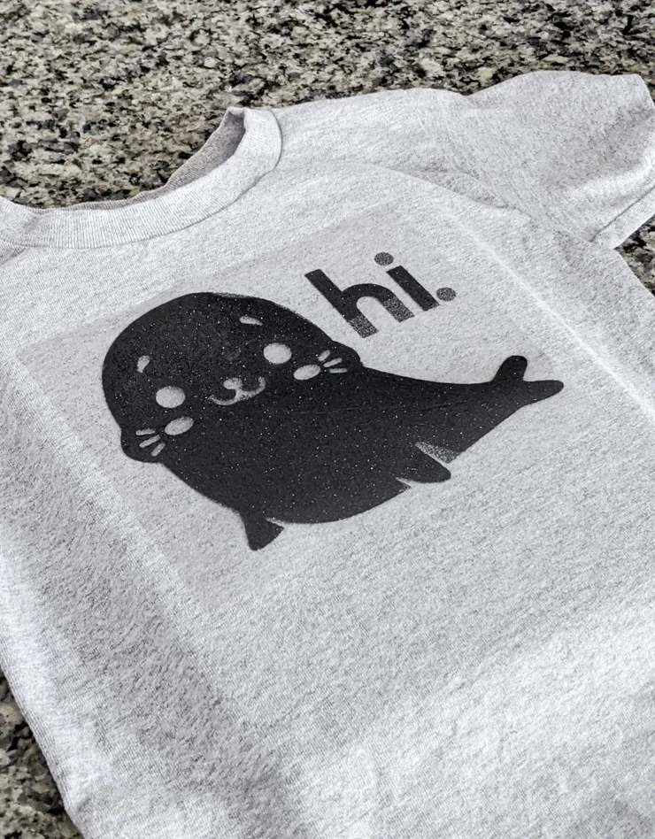 gray shirt with a glitter iron-on design of a seal saying hi