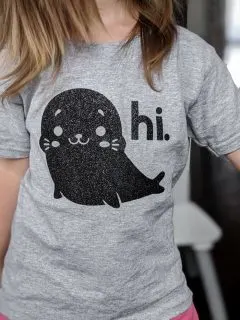 gray shirt with a glitter iron-on design of a seal saying hi
