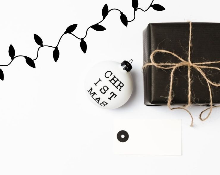 black and white holiday flat lay with christmas lights, an ornament, a present, and a gift tag