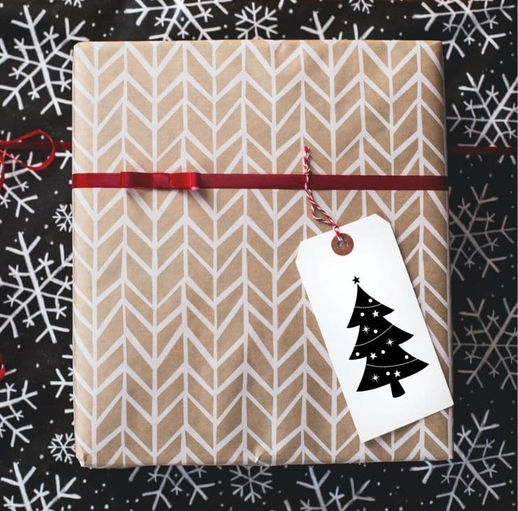 White and brown wrapped gift with a tag that has a Christmas tree on it