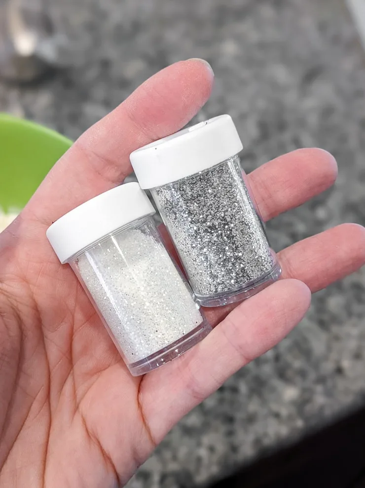 two bottles of glitter in a hand