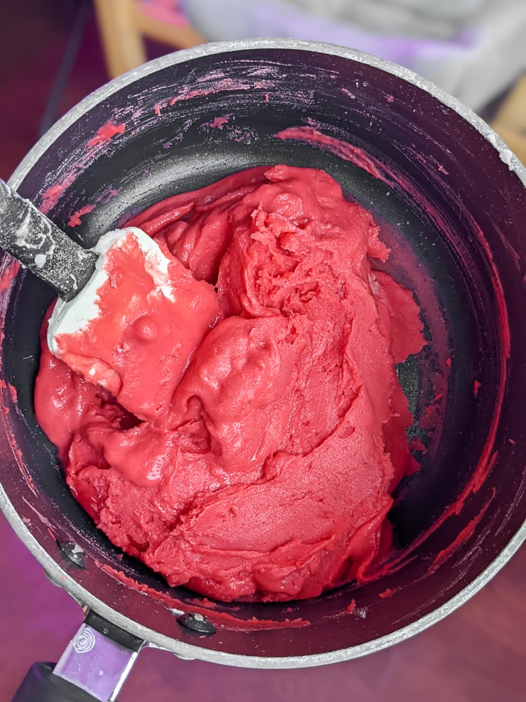 mixing bright red homemade playdough in a pan