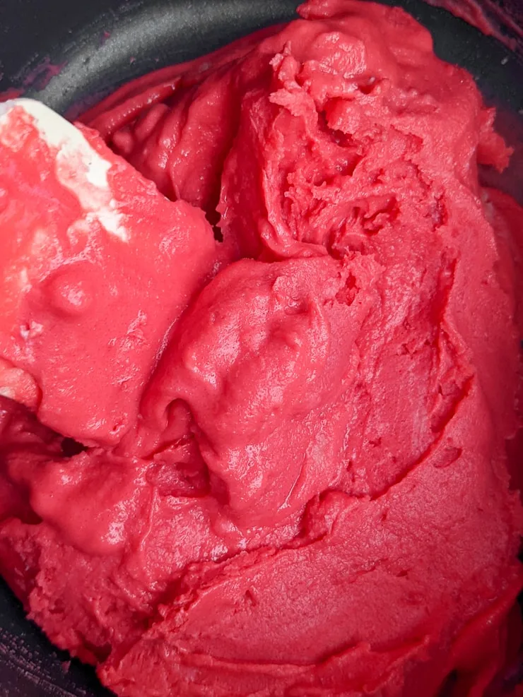 mixing bright red homemade playdough in a pan