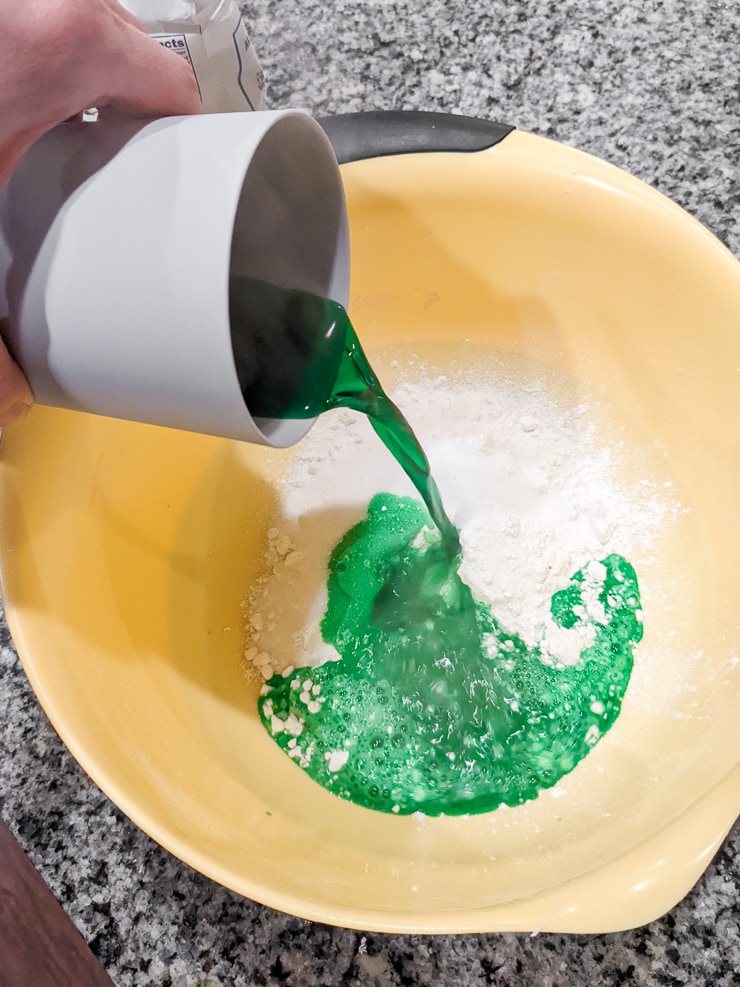 pouring green-colored lemon juice into the flour mixture