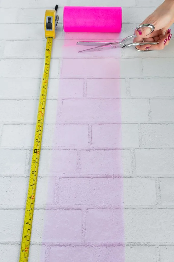 cutting a piece of pink tulle from a roll