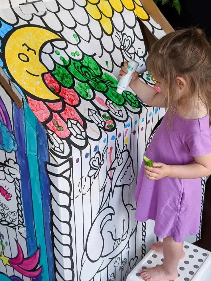 little girl coloring a colorable cardboard playhouse