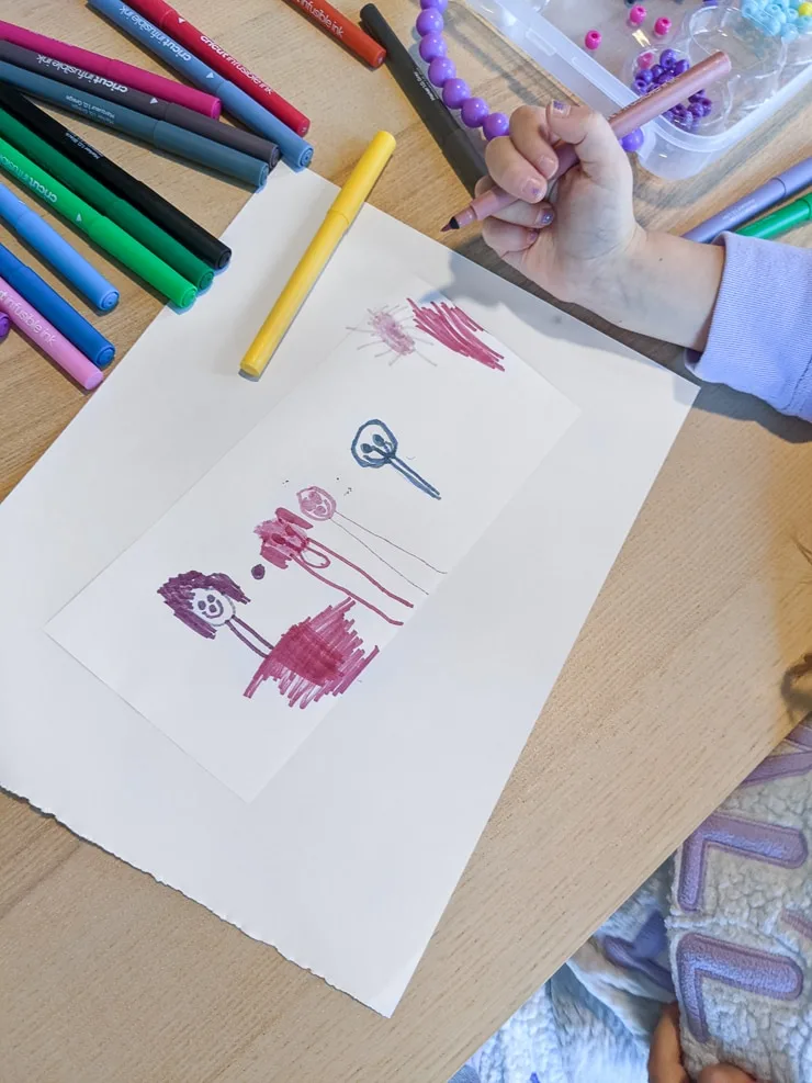 child drawing a picture with markers
