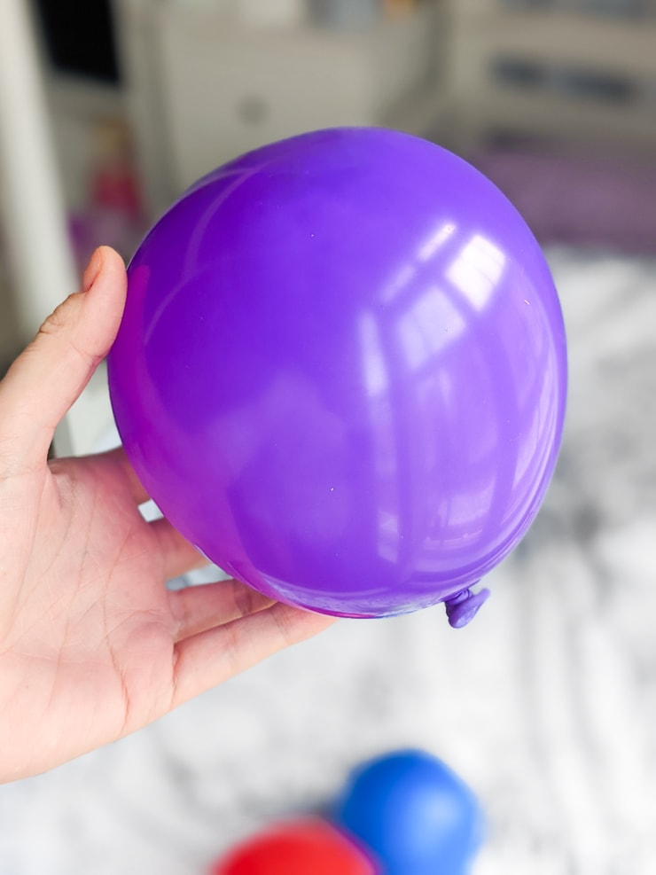 hand holding a purple balloon