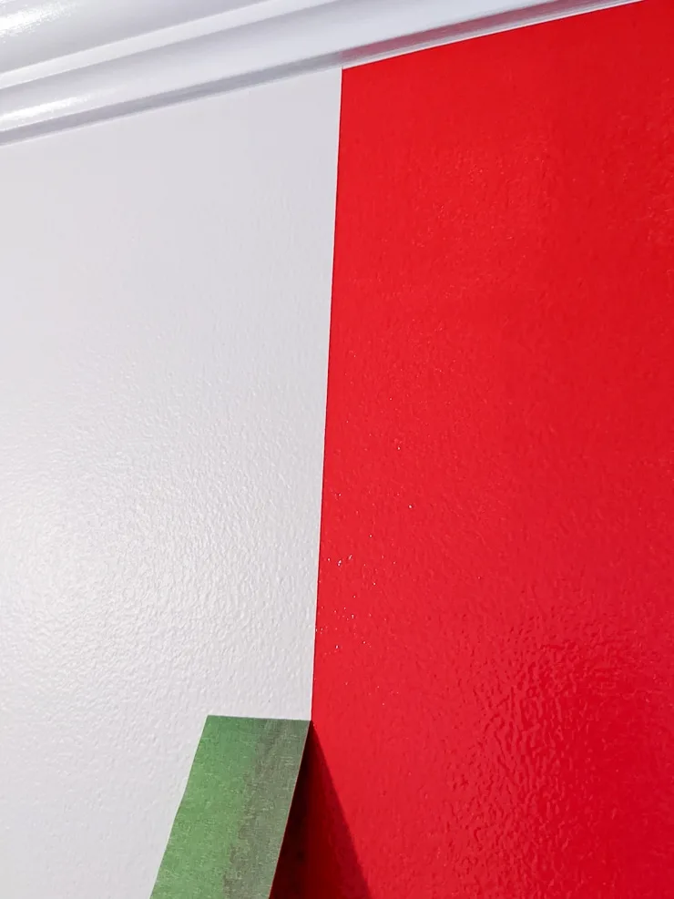 removing frogtape from a red-painted design on a wall