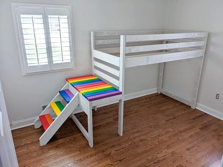 white loft bed with rainbow steps in a kids room
