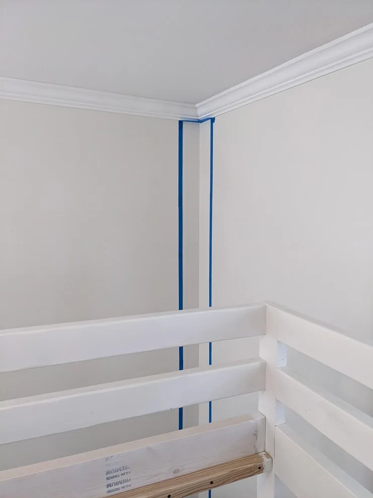 adding painter's tape onto a plain white wall to paint a stripe