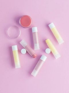 collection of DIY lip balm in containers on pink background