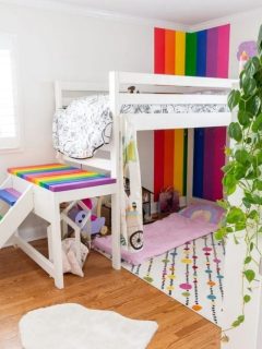 rainbow themed kids room with painted rainbow striped wall