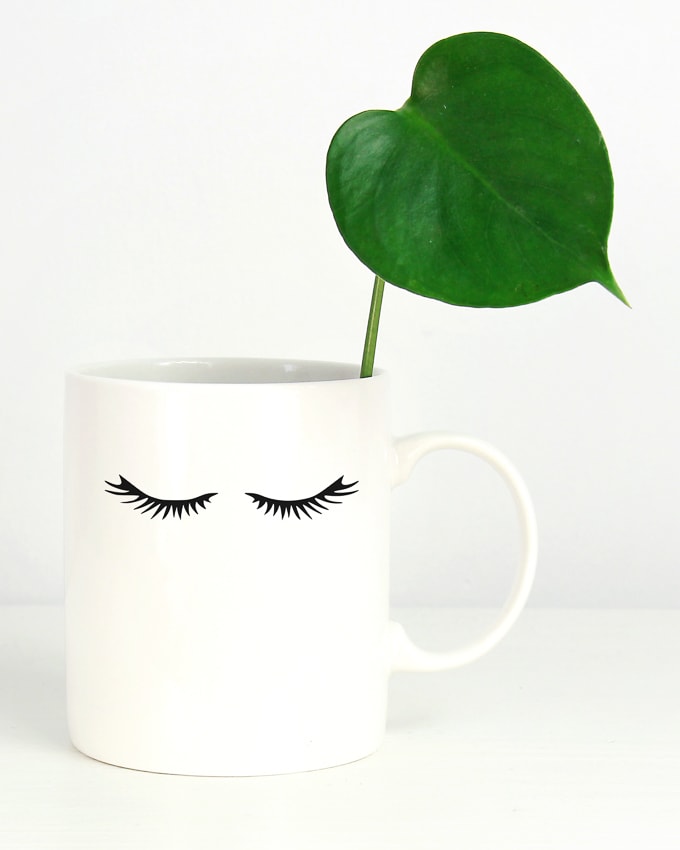 white mug with black eyelash decals on it